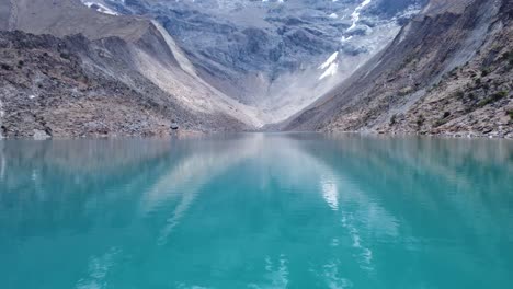 calm blue waters of humantay lake with rocky mountains in peru