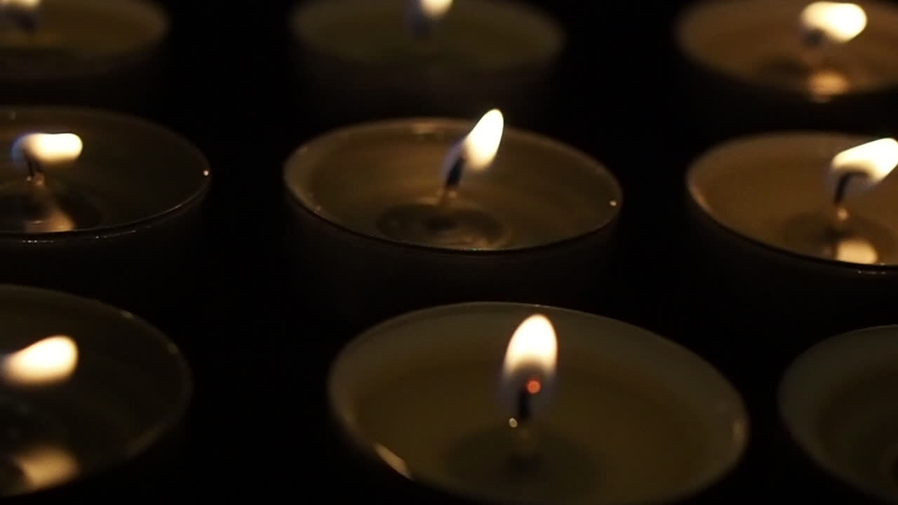 Candele nel buio, primo piano macro in slow motion con carrellata.