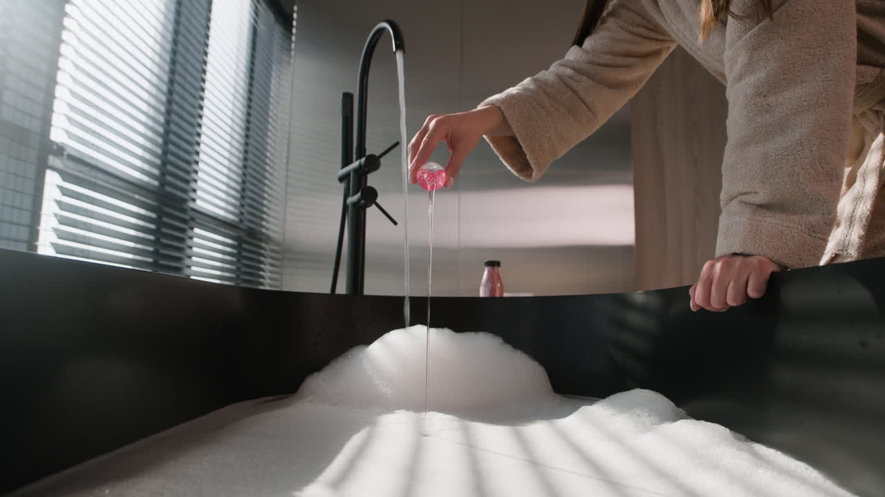 Woman Adding Pink Liquid to a Bathtub with Bubbles