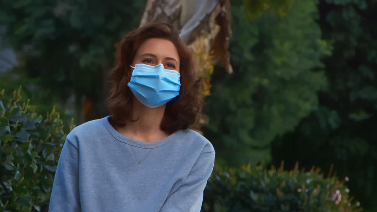 [cámara utilizada: canon c300] mujer caucásica feliz al aire libre usando una máscara facial y acariciando a su perro