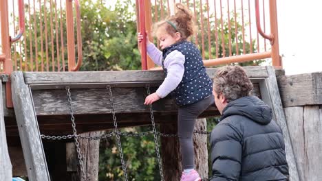 kids climbing with adult assistance outdoors