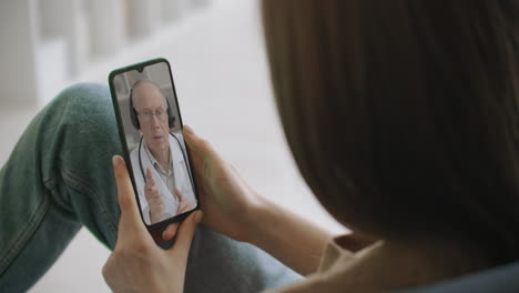 Woman-using-medical-app-on-smartphone-consulting-with-doctor-via-video-conference.-Female-using-online-chat-to-talk-with-family-therapist-and-checks-possible-symptoms-during-pandemic-of-coronavirus.