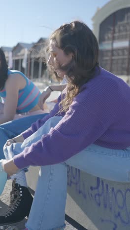 young women friends sitting and chatting outdoors