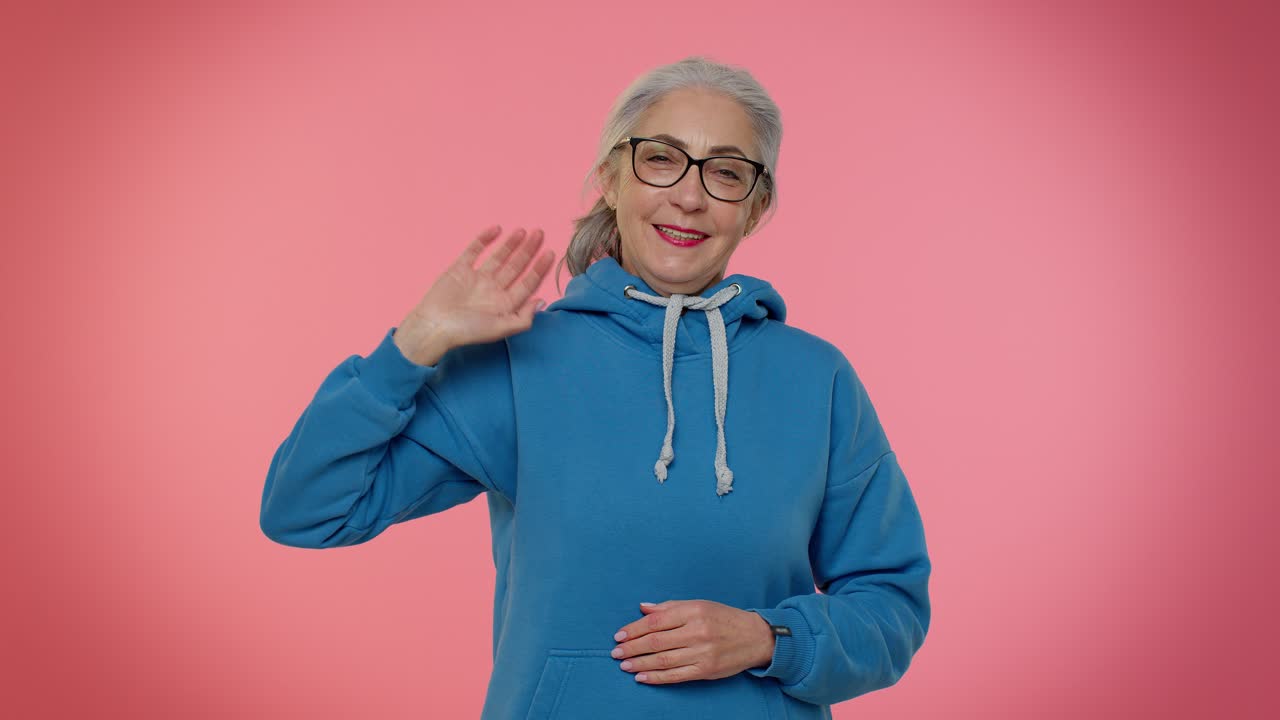 mujer mayor feliz y amigable agita la palma de la mano en el gesto de saludo da la bienvenida a alguien emociones positivas