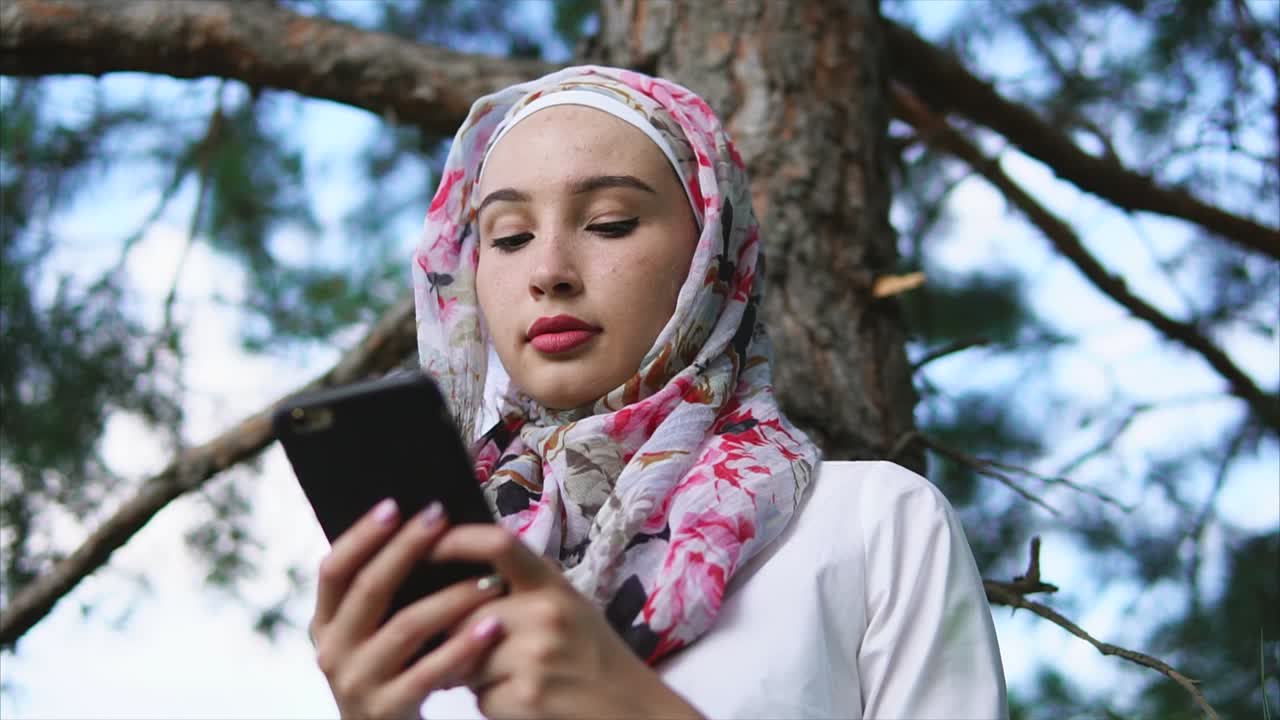 Ormanda akıllı telefon kullanan genç Müslüman kadın
