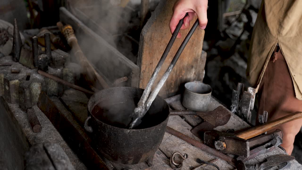 Blacksmith puts hot metal into pot of water