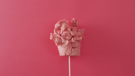 Video-Von-Marshmallow-Auf-Einem-Stock,-Der-Auf-Einer-Rosa-Oberfläche-Liegt