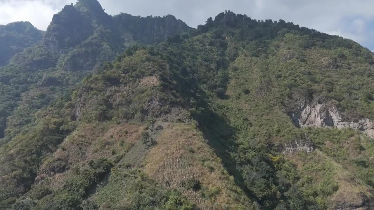 vista panorámica de una escarpada ladera montañosa en guatemala cubierta de vegetación, tierras de cultivo en terrazas y vegetación natural