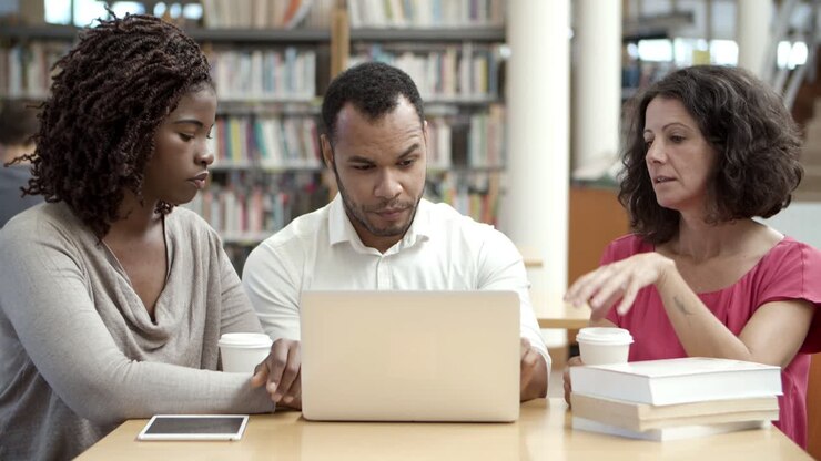 Seriöse reife Studenten arbeiten mit Laptop in einer öffentlichen Bibliothek