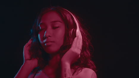 asian girl with headphones vibing with eyes closed in neon light