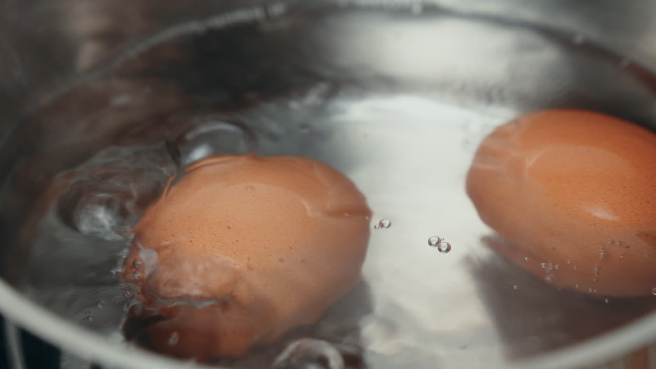Two eggs boiling in water on a stovetop pot