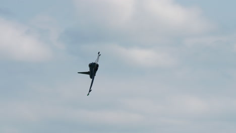military jet fighter executing a fast roll maneuver in the sky during flight performance