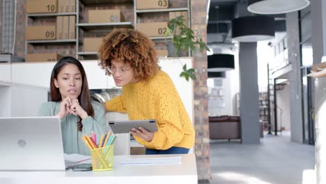 felices colegas femeninas diversas usando computadoras portátiles y tabletas hablando en el escritorio, espacio de copia, cámara lenta