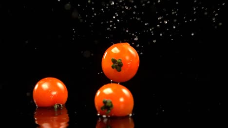tomates cayendo en el agua contra un fondo negro 4k