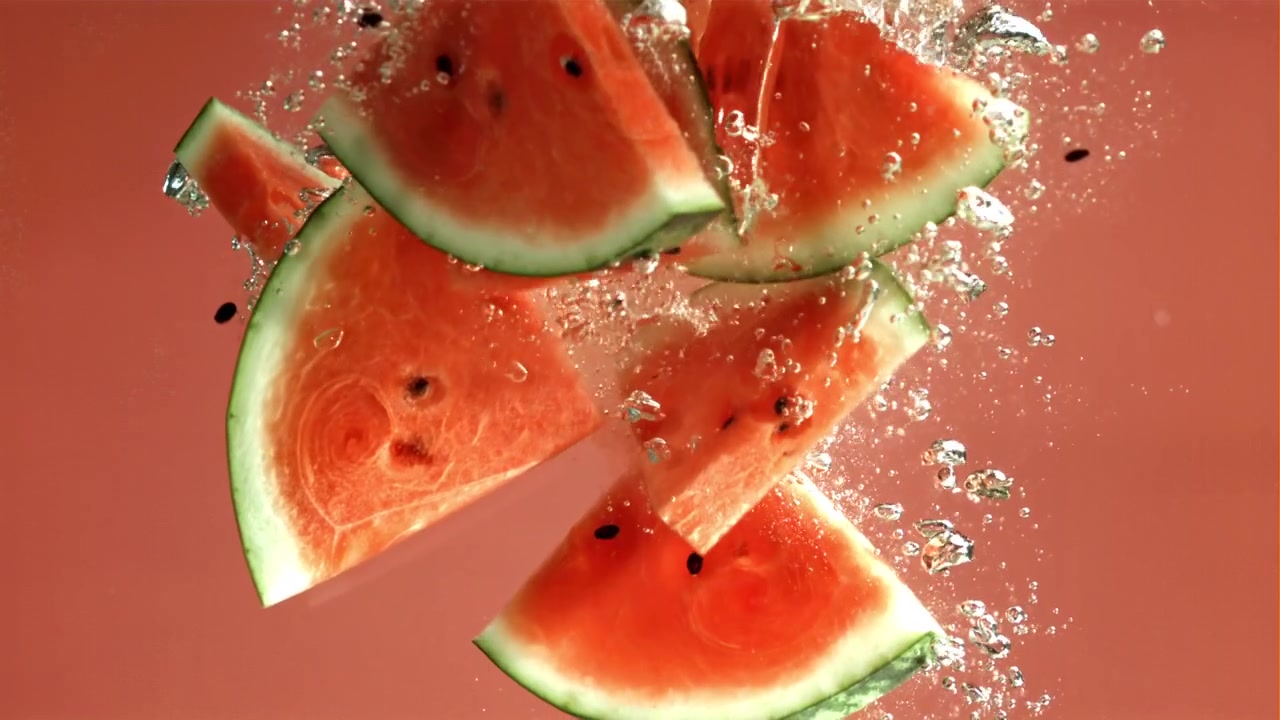 Ferske vannmelonskiver faller ned i vann med bobler
