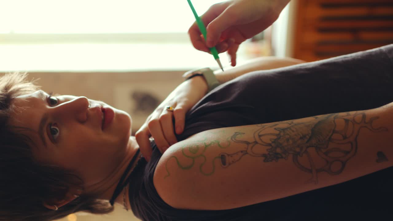 Woman Discussing Design of Tattoo with Artist Drawing on Her Skin