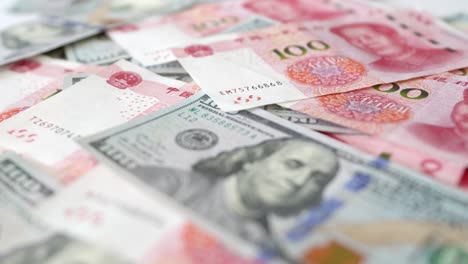 Hundred-yuan-RMB-and-hundred-USD,-Chinese-and-American-paper-money,-flowing-on-the-table,-close-up,-time-lapse