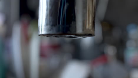 slow drip from end of faucet tap with bokeh background