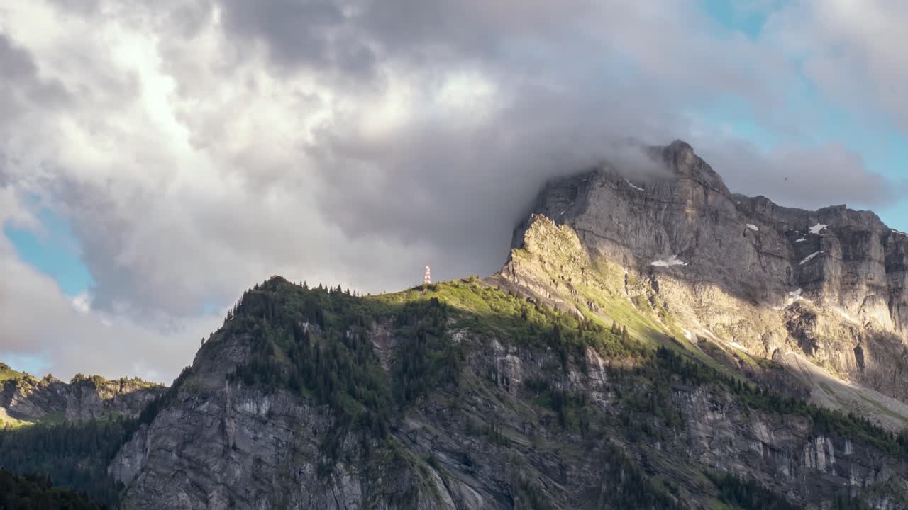 lapso de tiempo, nubes dramáticas chocan contra un pico rocoso en los alpes durante la puesta del sol