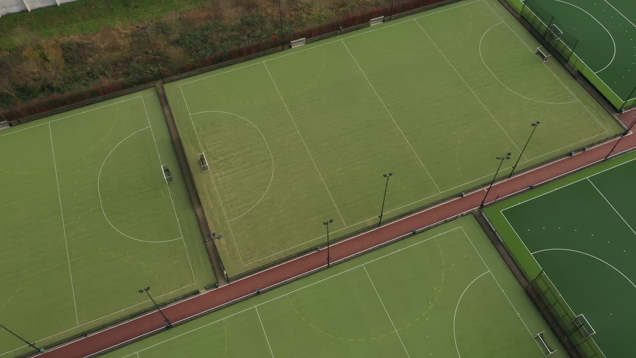 воздушный вид, который вращается вокруг комплекса из нескольких спортивных полей с искусственной зеленой травой