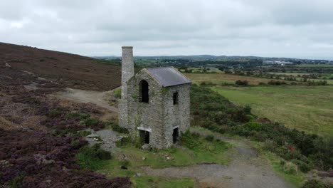 Parys-mountain-abandoned-brick-chimney-copper-mining-mill-stone-ruin-aerial-view-wide-left-orbit