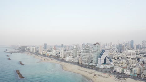 4k aerial - majestic cityscape pan up - tel aviv beach during sunset