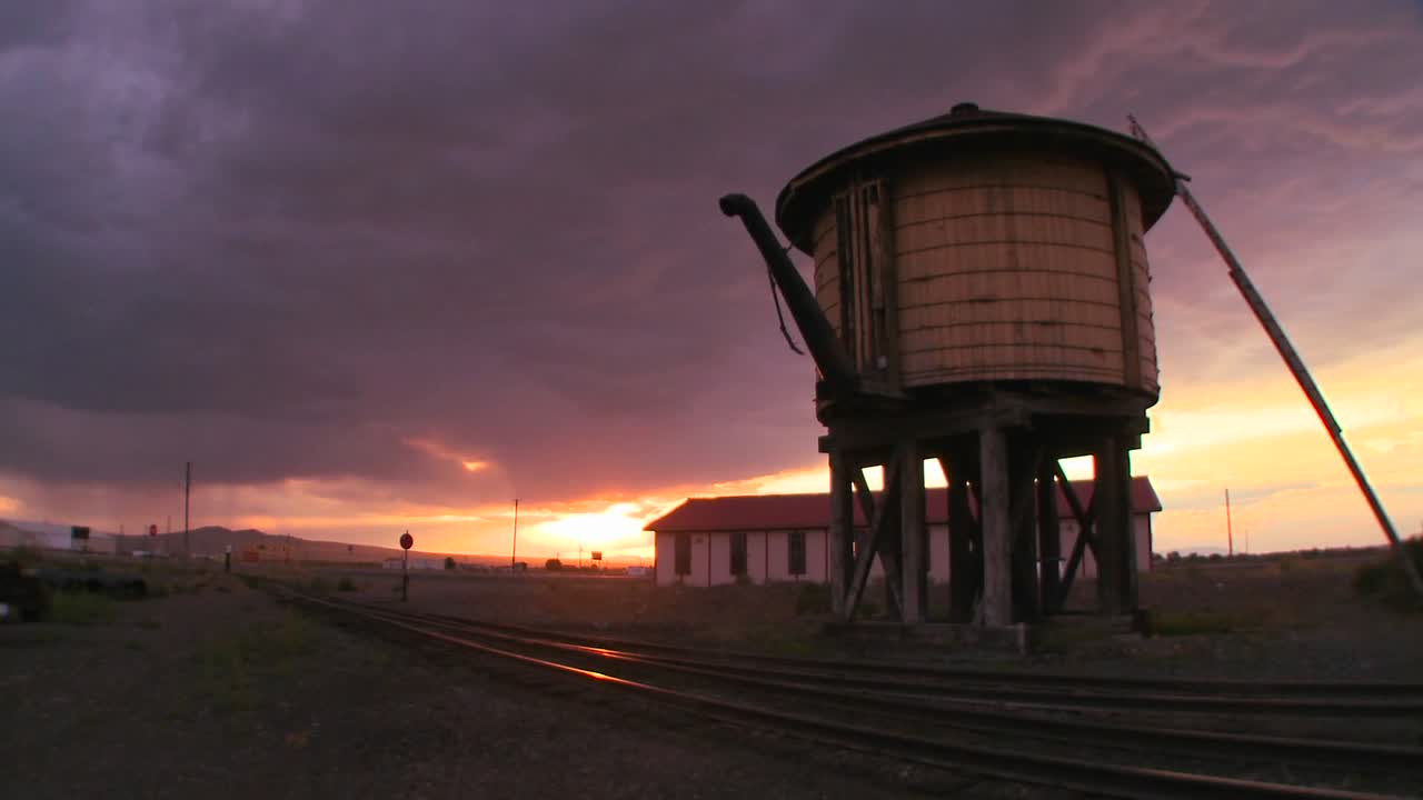 una torre de agua a lo largo de una vía férrea abandonada al atardecer 1