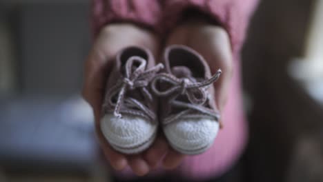 Weibliche-Hände,-Die-Babyschuhe-Zeigen.-Gestrickte-Schuhe-Für-Kinder