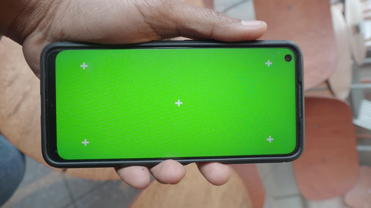 persona que sostiene un teléfono inteligente con una pantalla verde