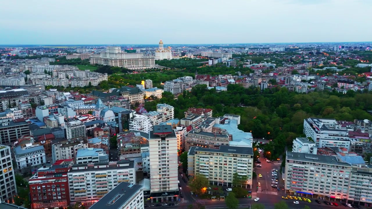 Il drone orbita sul posto rivelando l'intero paesaggio urbano di Bucarest con i punti di riferimento illuminati durante l'ora blu.