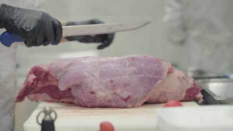 close-up view when a butcher slicing fresh meat with his hands and sharpen knife.