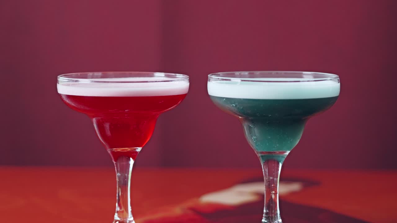 Cinematic slow zoom on colorful drinks standing on red surface with blur