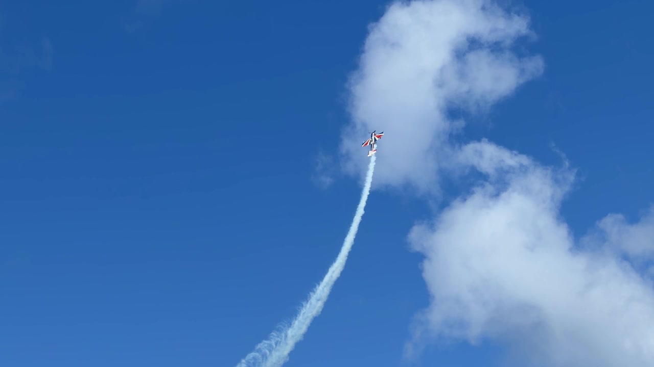 Propeller aircraft performs precision maneuvers with white smoke trails against a blue sky in Australia.