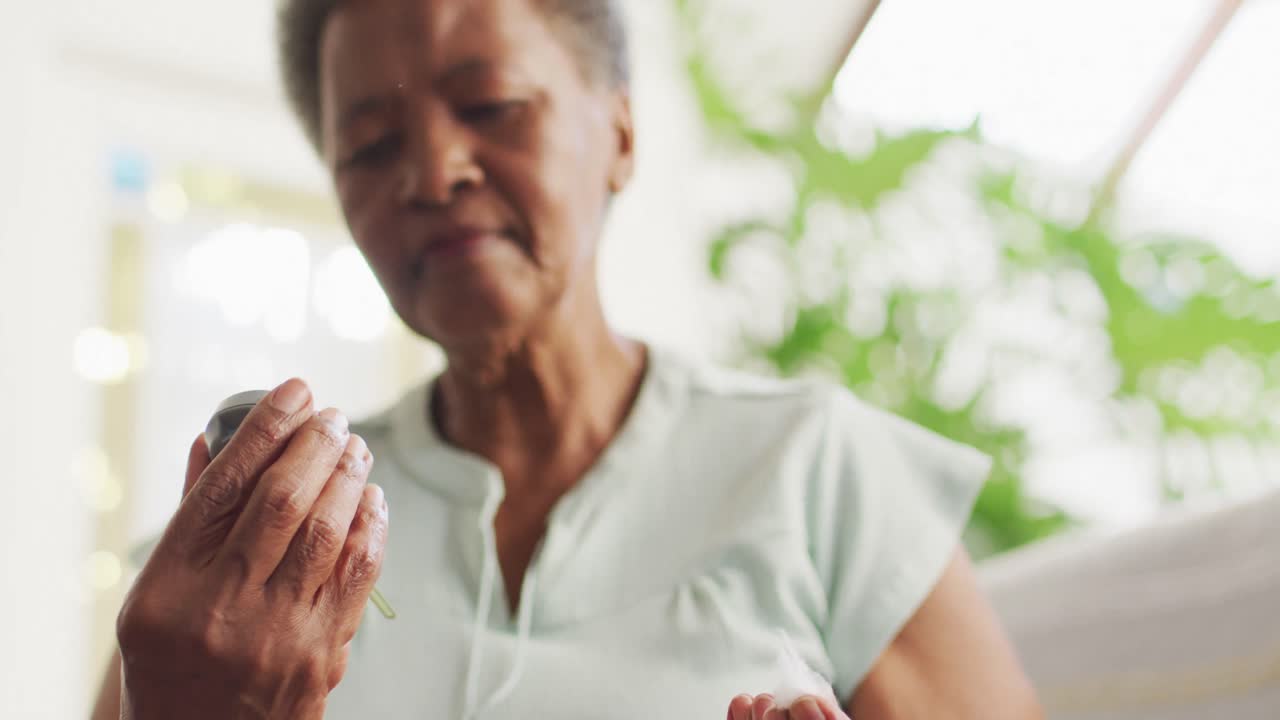 mujer afroamericana mayor que usa medidor de glucosa en casa