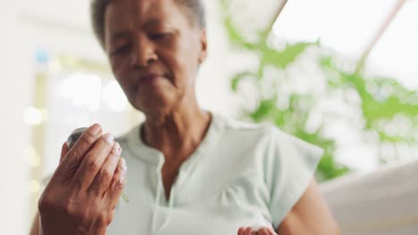 femme afro-américaine âgée utilisant un compteur de glucose à la maison
