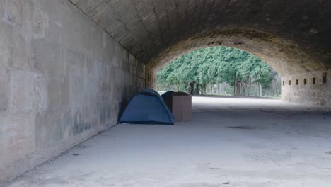 homeless camping under an archway in a park