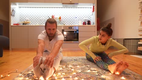 couple stretching at home with christmas lights