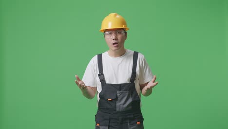 Wondering Asian Man Worker Wearing Goggles And Safety Helmet Saying Why And Standing Doubtfully In The Green Screen Background Studio