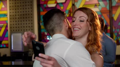 woman checking her mobile phone while embracing a man