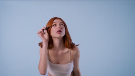 one model crosses in front of the camera. the other opens a mascara, applies it to both eyelashes, shows the product and exits playfully.
