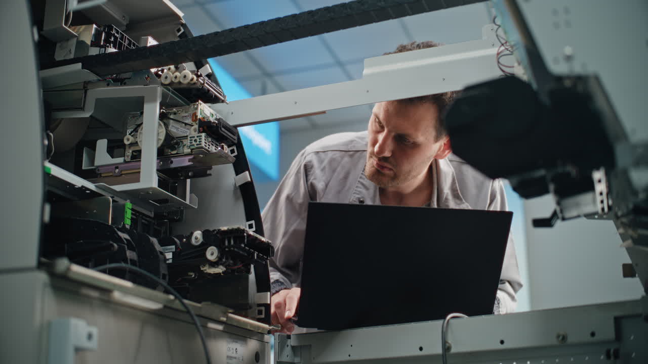ATM Repair Technician Working on a Machine with a Laptop