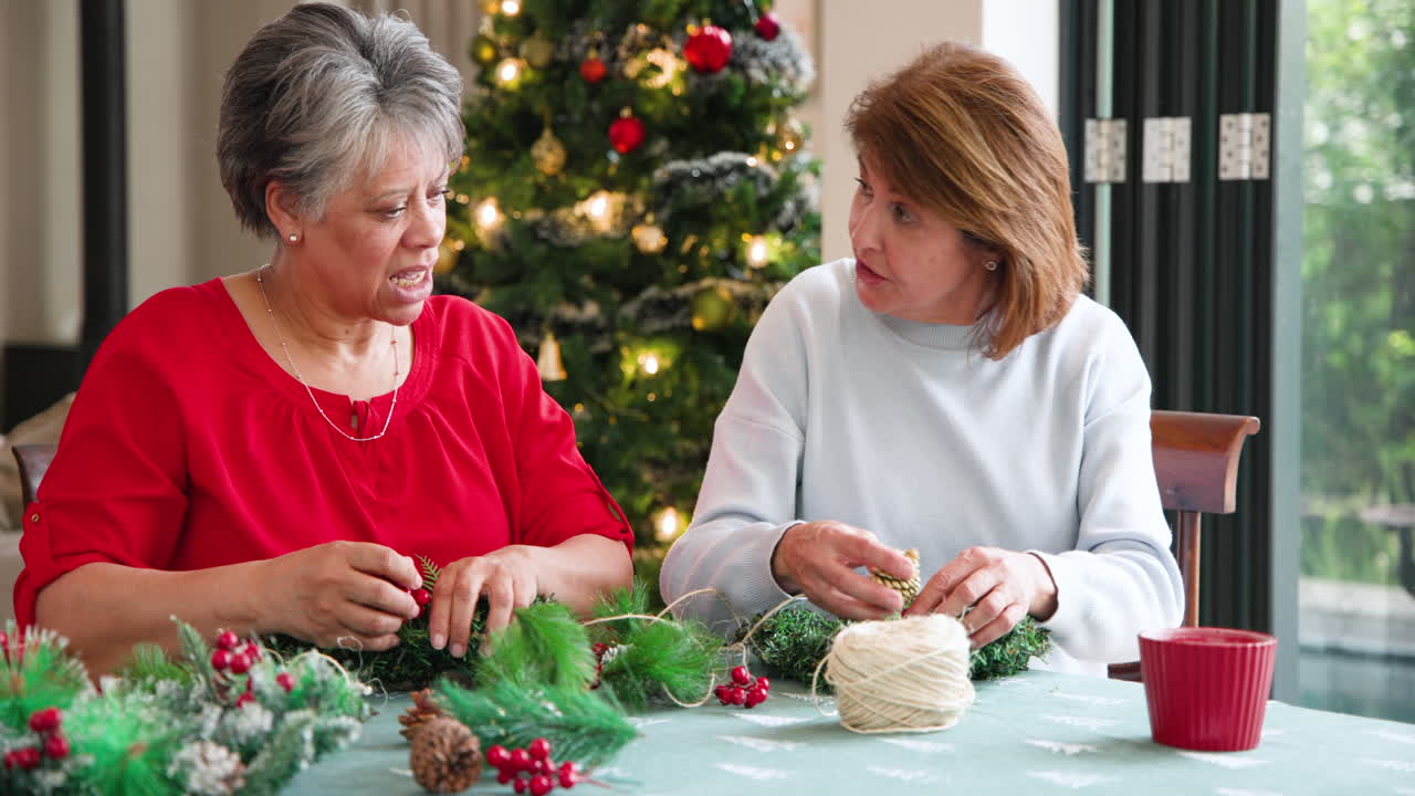Senior women crafting Christmas wreaths together at home, enjoying festive time