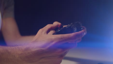 Playing-video-games-in-a-darkened-room-with-an-anamorphic-lens-flare-on-a-small-controllers-buttons-playing-quickly