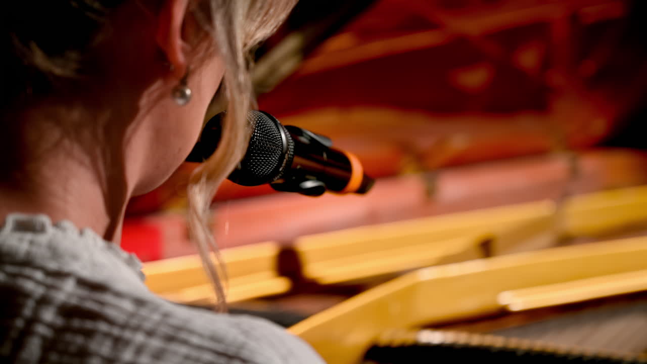 Woman singing into the microphone and playing a red piano