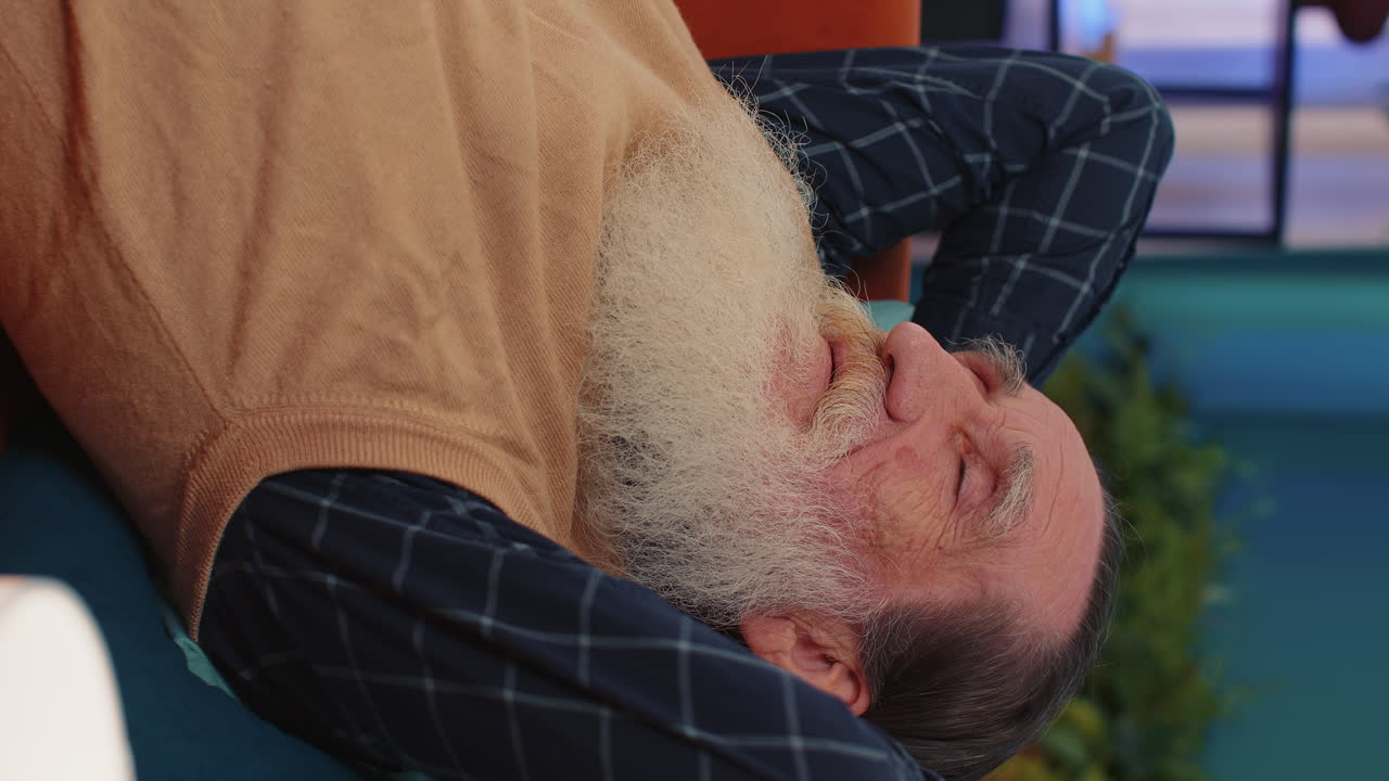 cansado un anciano anciano acostado en la cama tomando un descanso en casa, durmiendo, quedándose dormido en el sofá