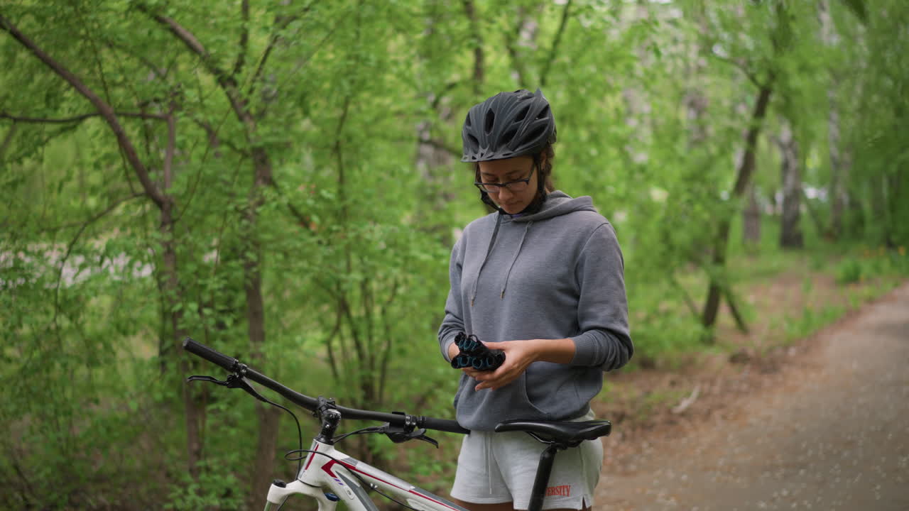 Mentre si prepara in silenzio per un giro in bicicletta, una copertura verde protegge il ciclista. Un ciclista tranquillo sotto una tettoia verde sistema la sua attrezzatura prima di partire.
