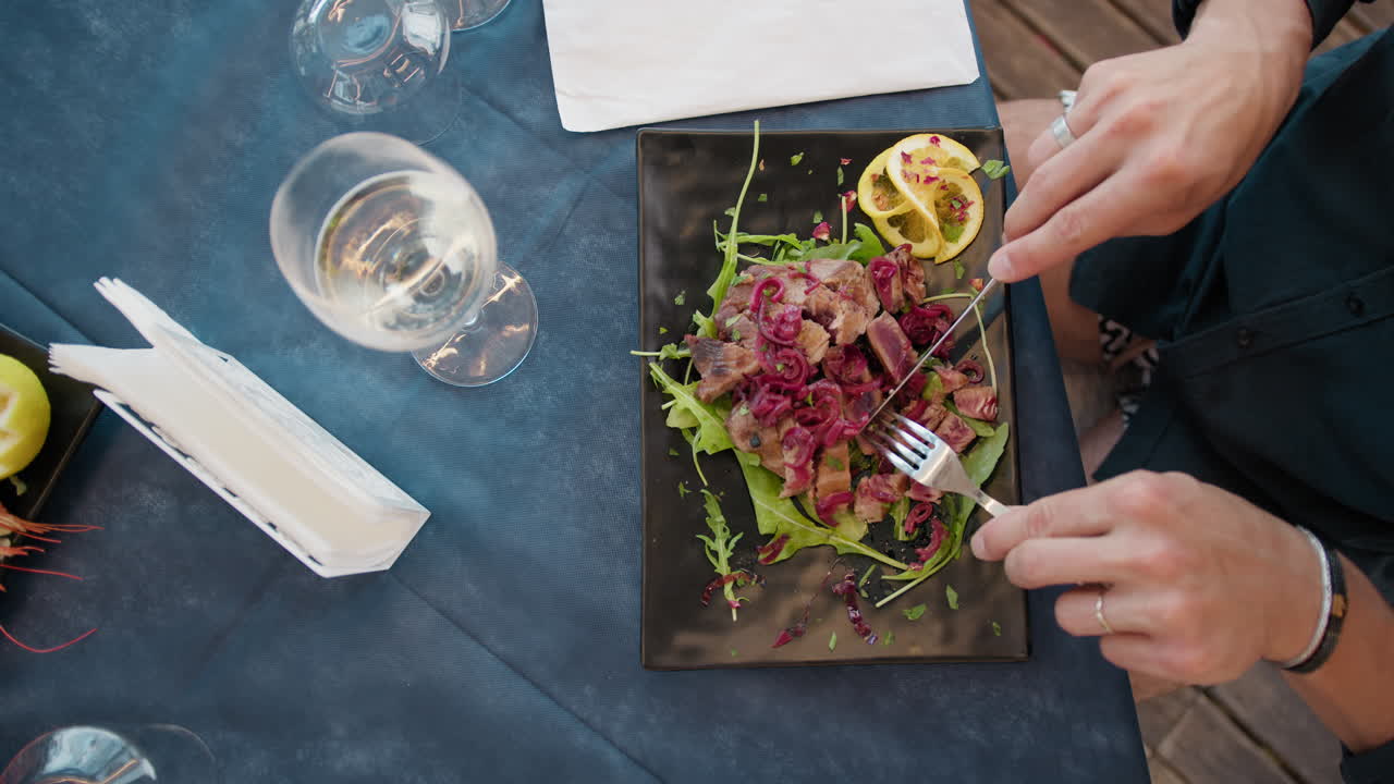 Hands Of Man With Fork And Knife Cutting The Tuna On The Beach Resort Table