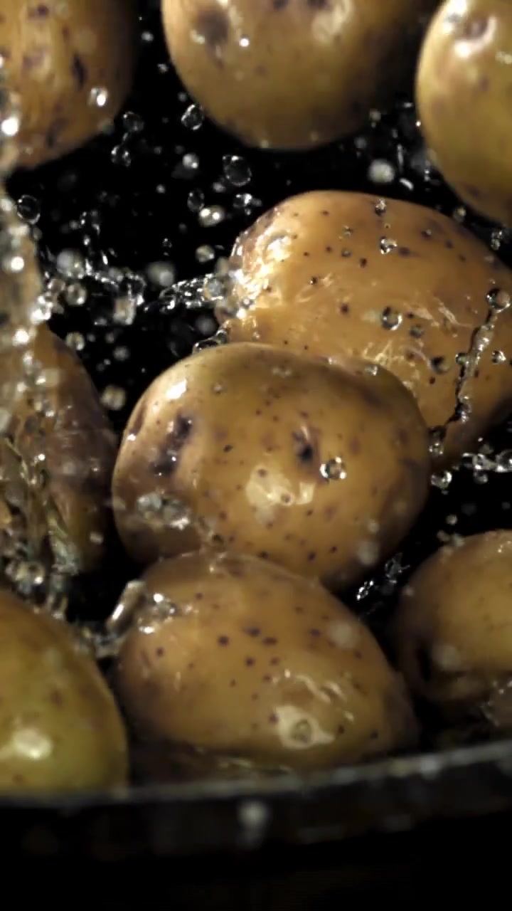 Patate fresche che cadono e schizzano nell'acqua al rallentatore
