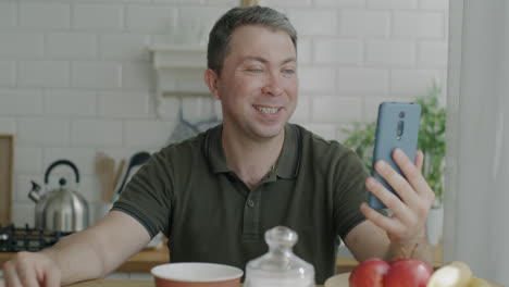 man having a video call in the kitchen during breakfast