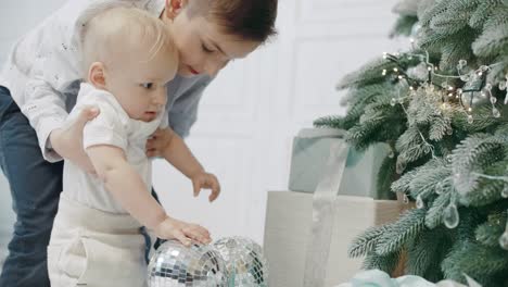 two brothers touching christmas tree in living room.